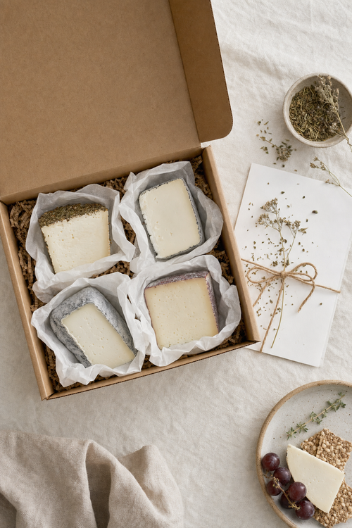 Open quarterly cheese subscription box with four wedges of artisan goat cheese